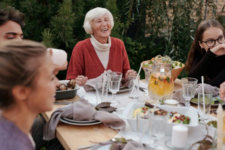 Mujer mayor sonriendo con su familia, representando los beneficios auditivos