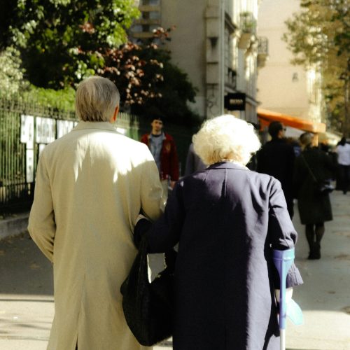 Parejas mayores abrazadas en la calle, símbolo de bienestar y vitalidad gracias a las claves auditivas del envejecimiento activo.