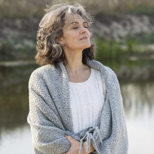 Mujer serena al aire libre con los ojos cerrados, transmitiendo paz y bienestar tras haber aprendido cómo comparar audífonos y elegir el más adecuado.